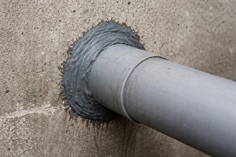 Rura przechodząca przez ścianę z widocznym uszczelnieniem